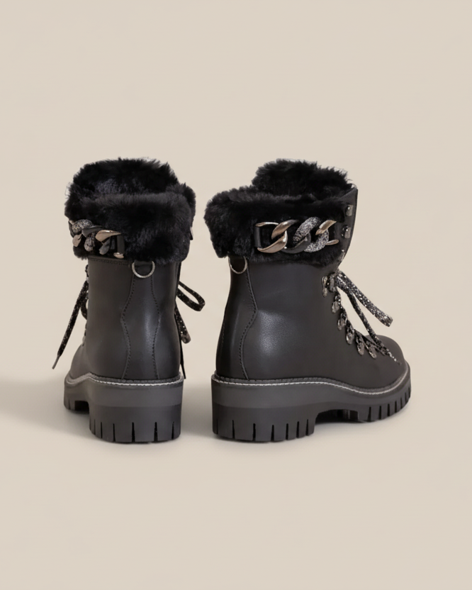 Black winter boots with fur trim and decorative elements on a white background