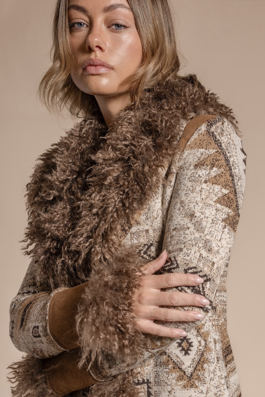 Woman wearing a patterned coat with a fur-lined hood against a beige background