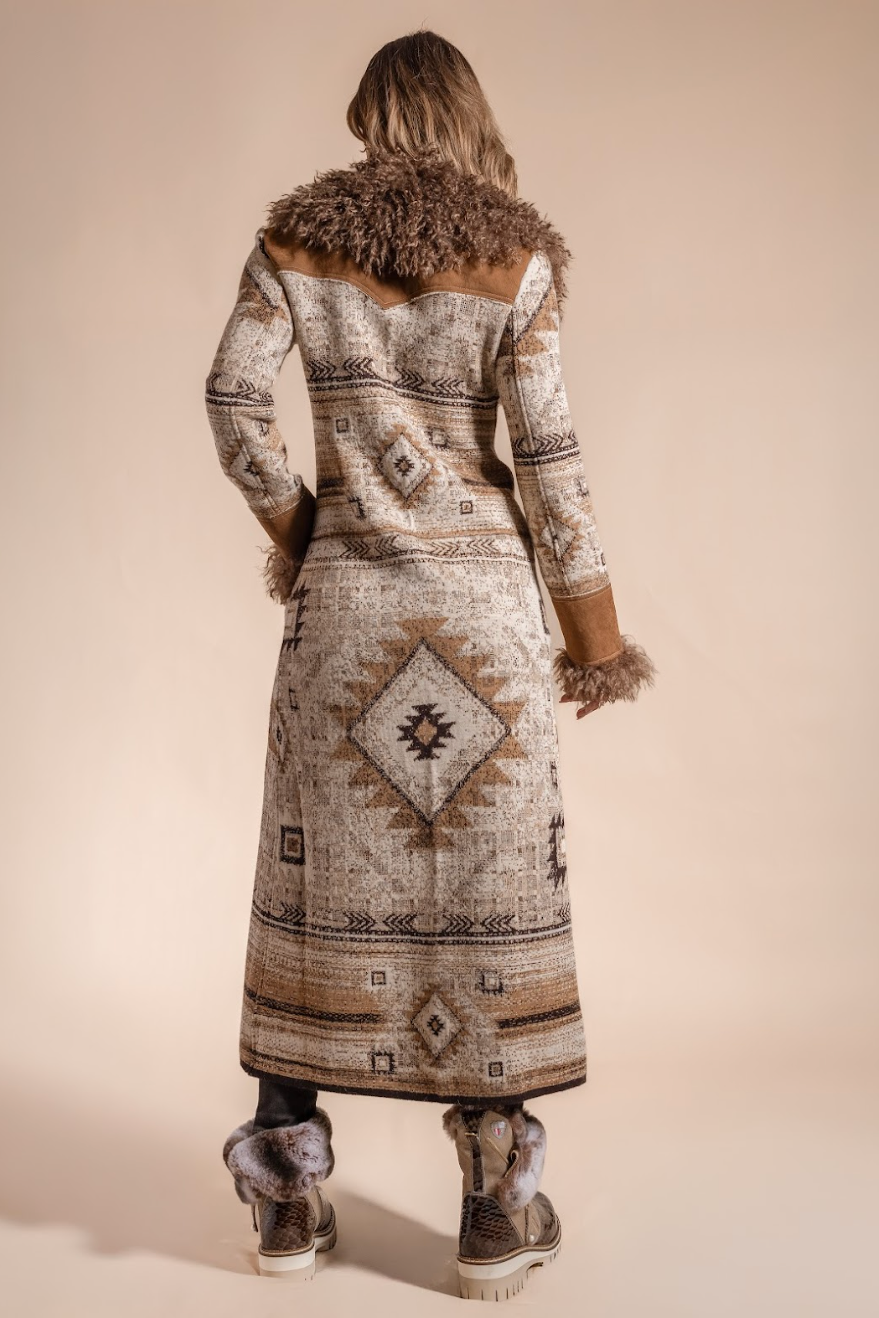 Person wearing a long patterned coat with fur trim on a beige background