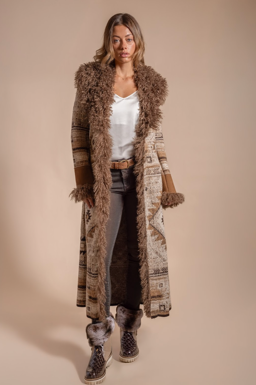 Woman wearing a long, patterned coat with fur trim on a beige background