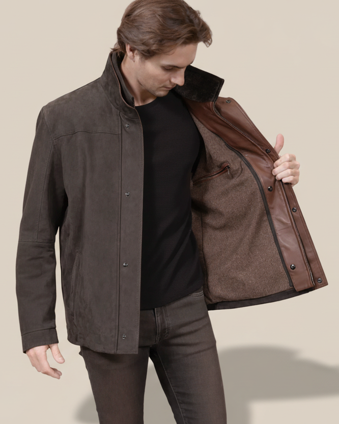 Man holding a brown leather jacket against a beige background