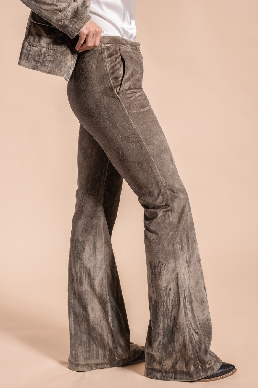 Person wearing gray flared jeans on a beige background