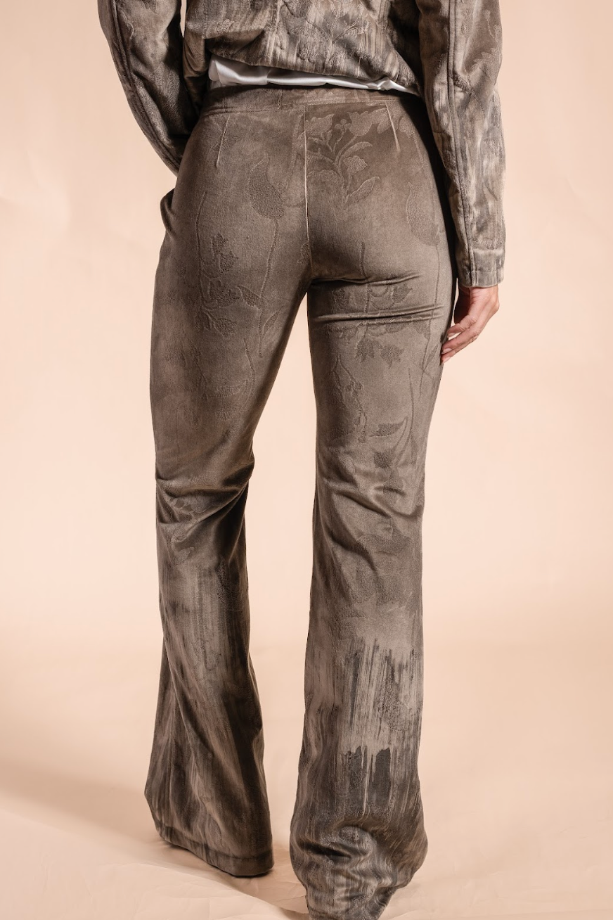 Person wearing washed brown floral pants on a beige background