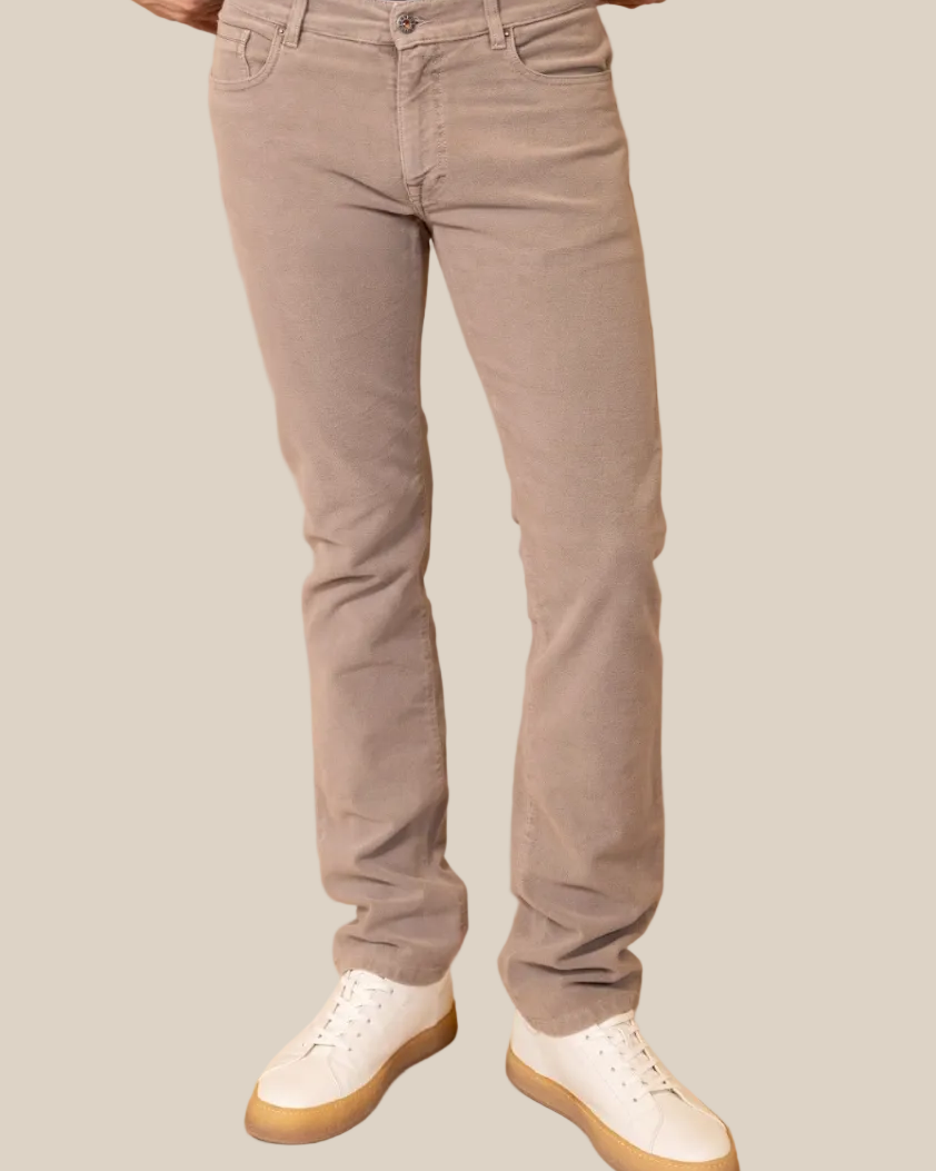 Person wearing beige pants and white sneakers on a beige background
