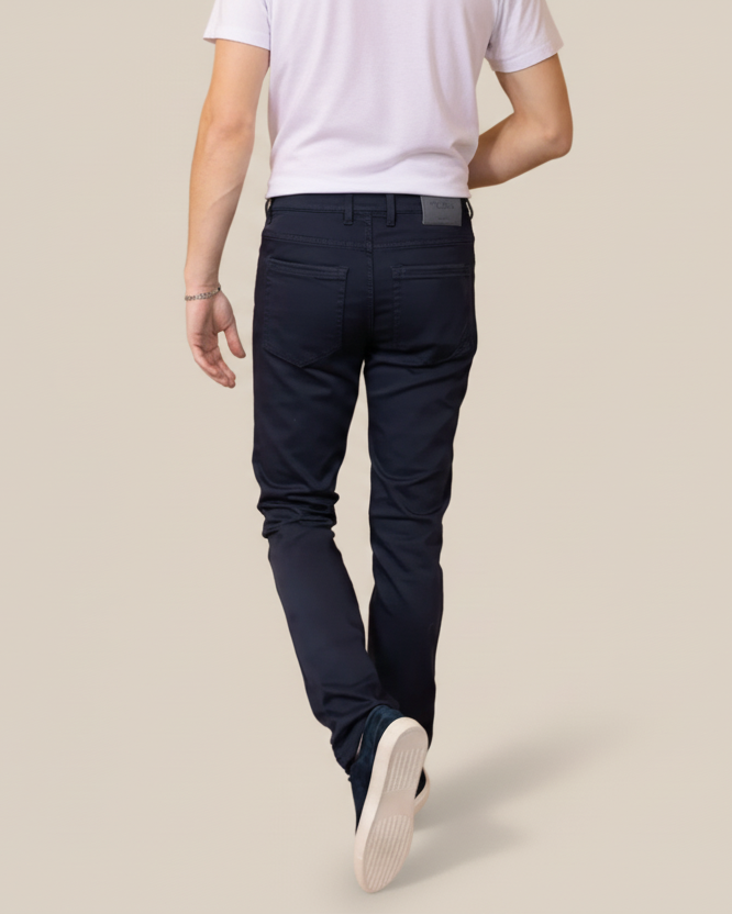 Person wearing navy pants and a white shirt on a beige background