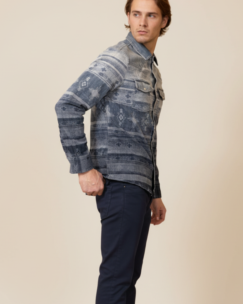 Man wearing a patterned denim shirt and dark pants on a beige background