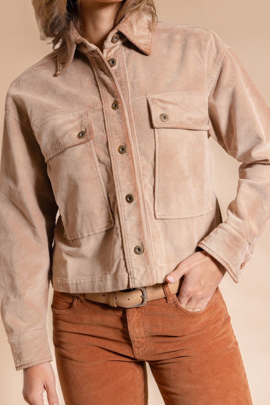Person wearing a beige jacket and brown pants on a beige background