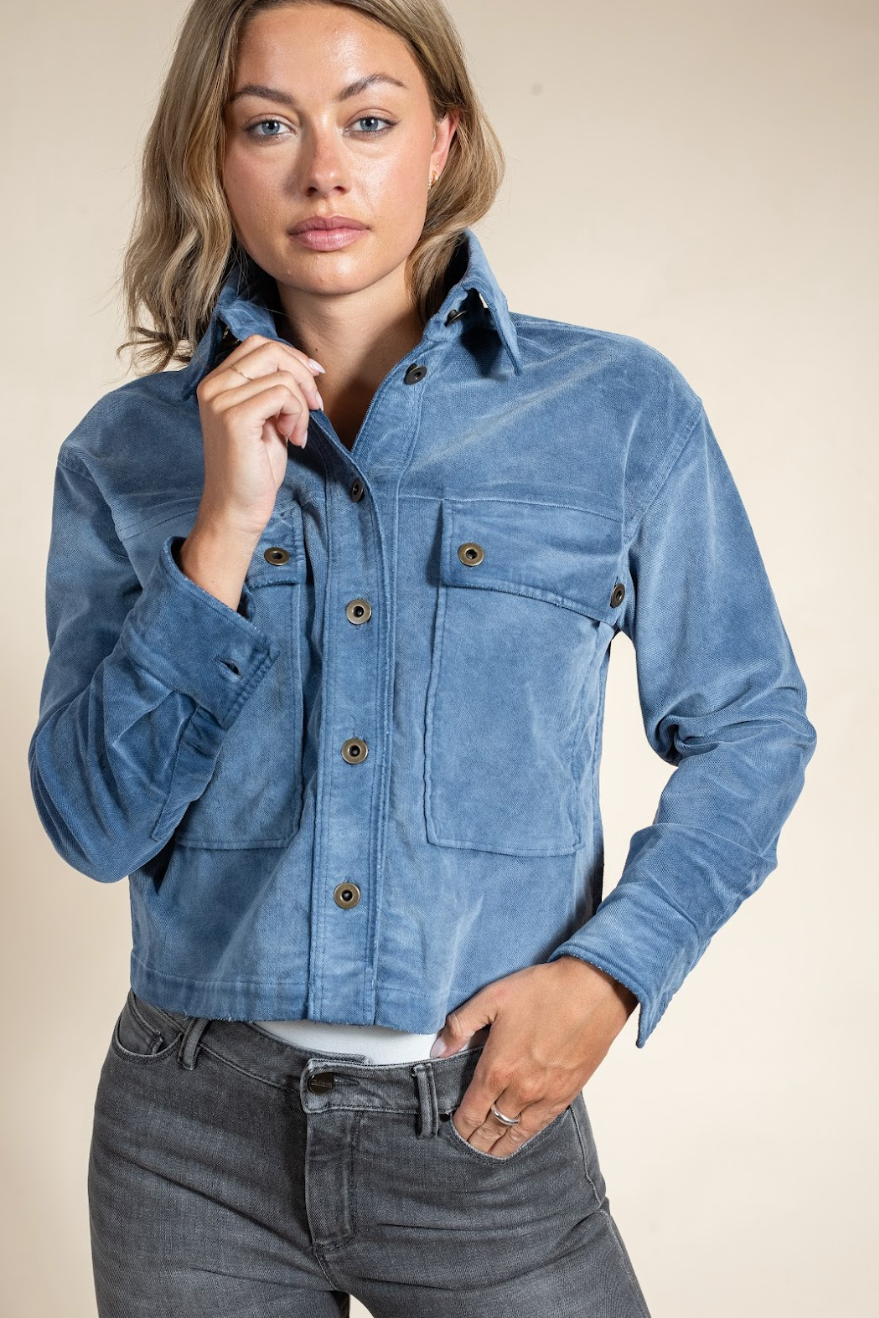Woman wearing a blue denim jacket against a beige background