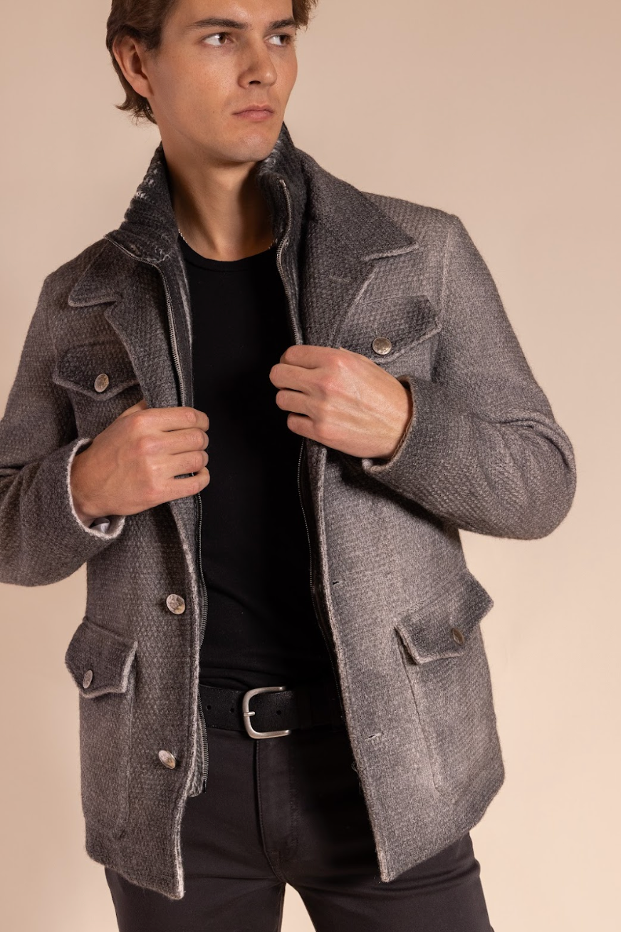 Man wearing a gray coat against a beige background