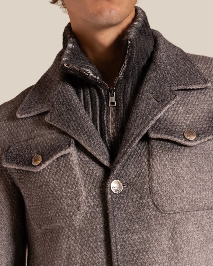 Man wearing a gray coat against a beige background