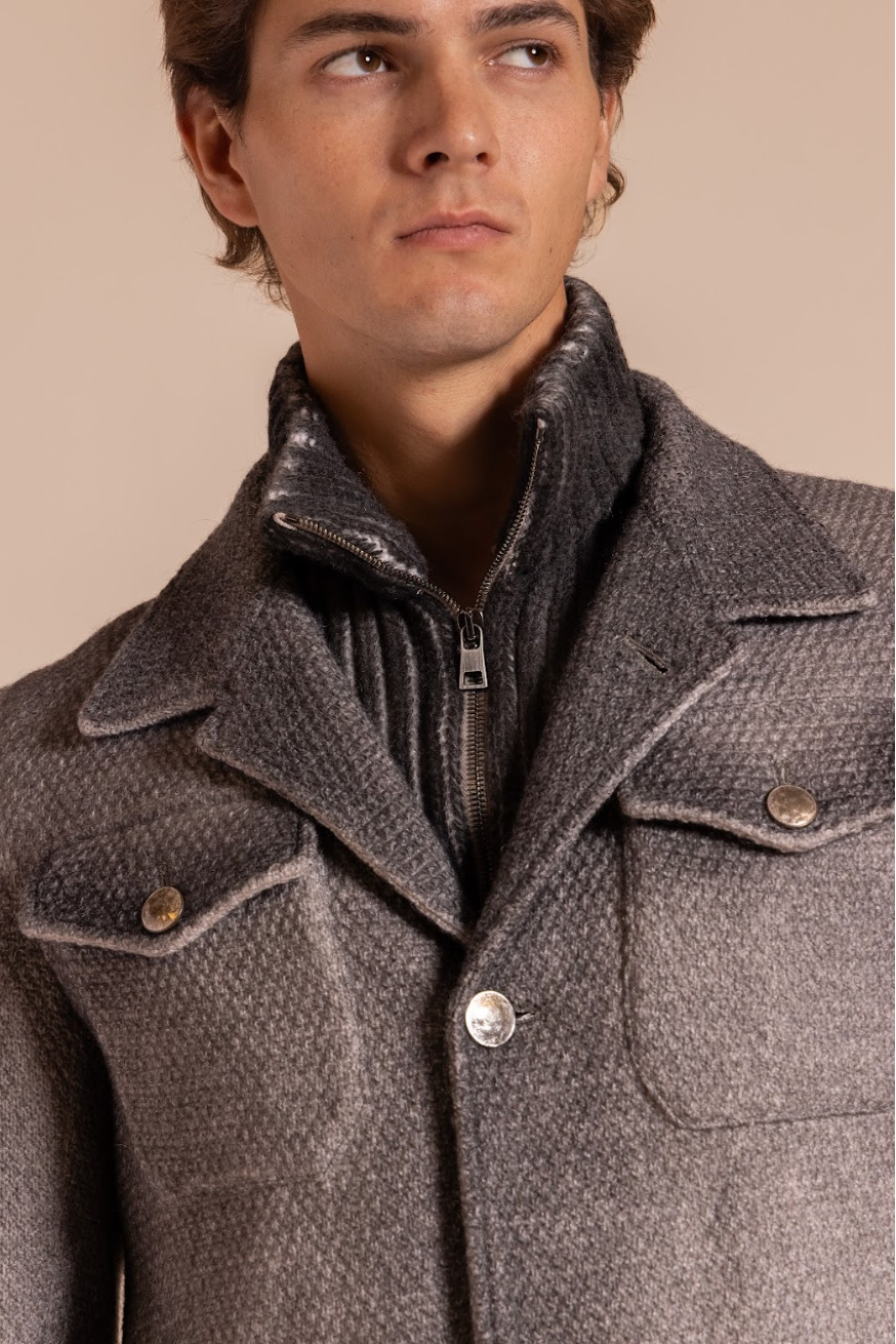 Man wearing a gray coat against a beige background