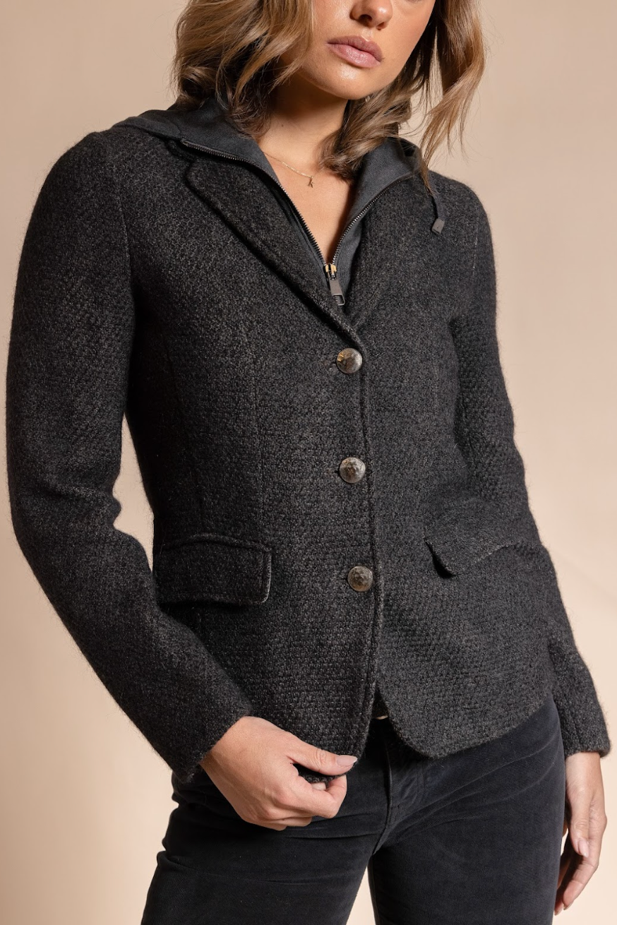 Dark gray blazer with buttons worn by a person on a beige background