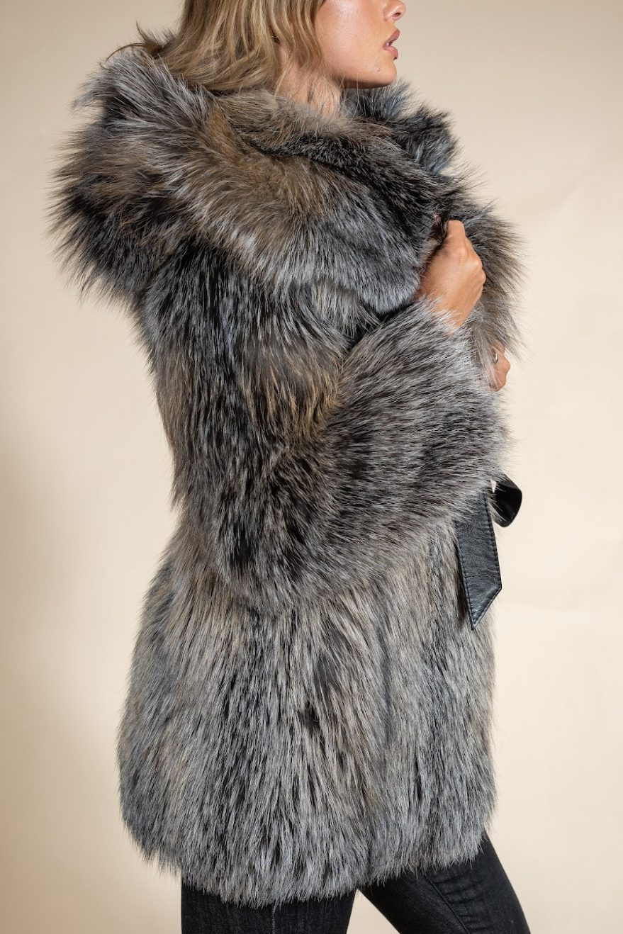 Person wearing a gray fur vest on a beige background