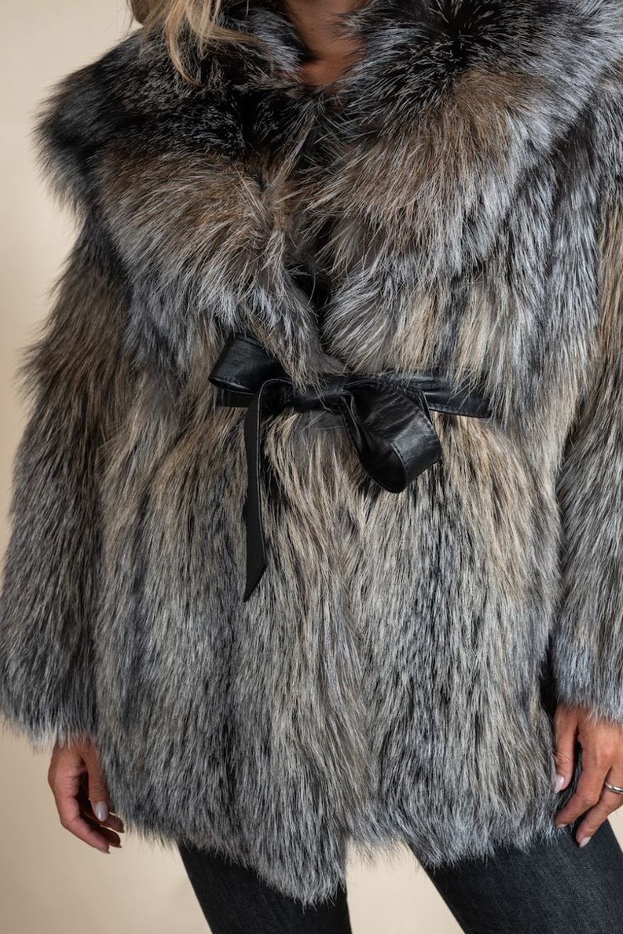 Close-up of a fur coat with a black bow on a beige background