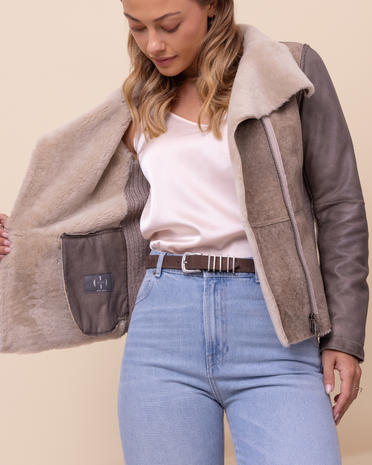 Woman wearing a brown and beige jacket with a neutral background