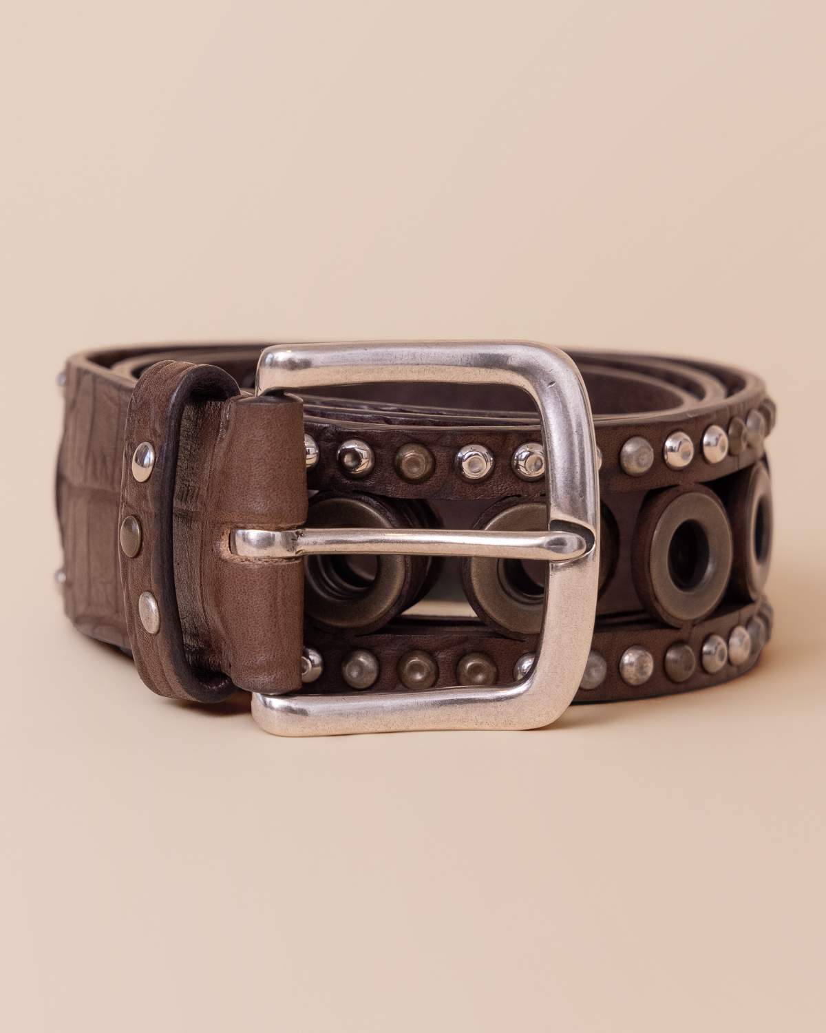 Brown leather belt with silver buckle on a beige background