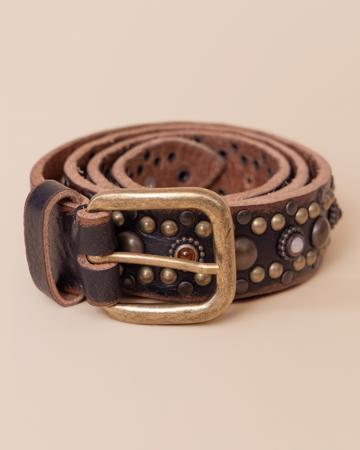 Brown leather belt with studded details on a beige background