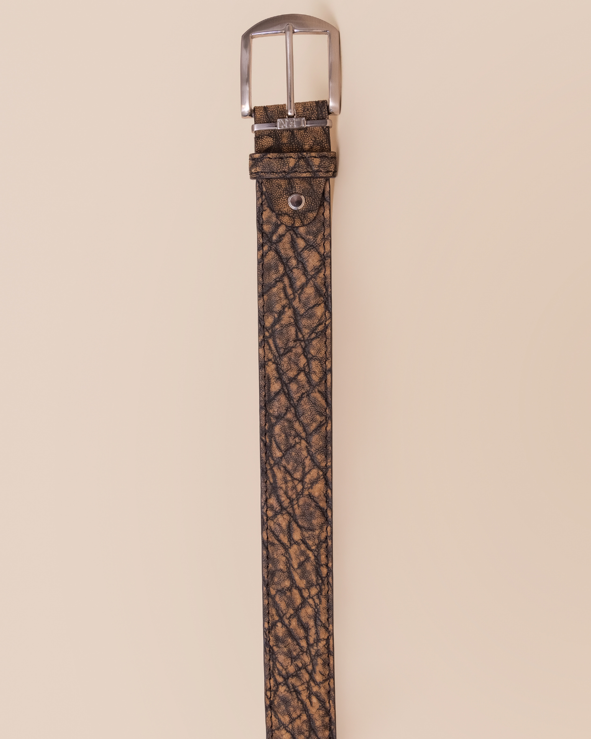 Brown leather belt with silver buckle on a beige background