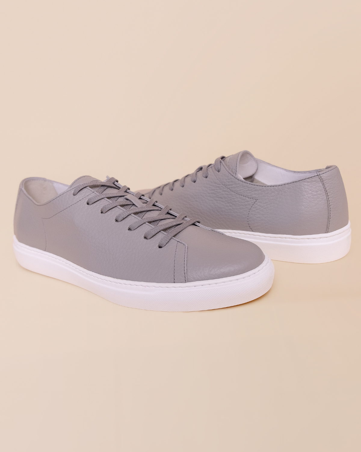Pair of gray sneakers with white soles on a beige background