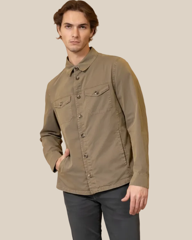 Man wearing a green jacket and dark pants against a beige background