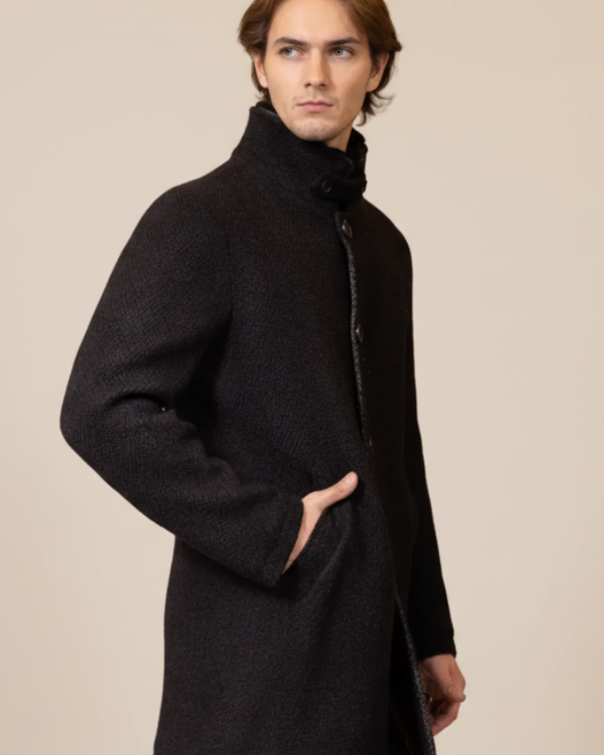 Man wearing a black coat against a brown background