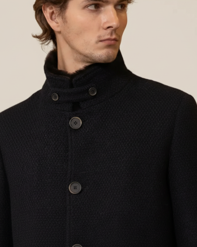 Man wearing a dark coat with button details on a plain background