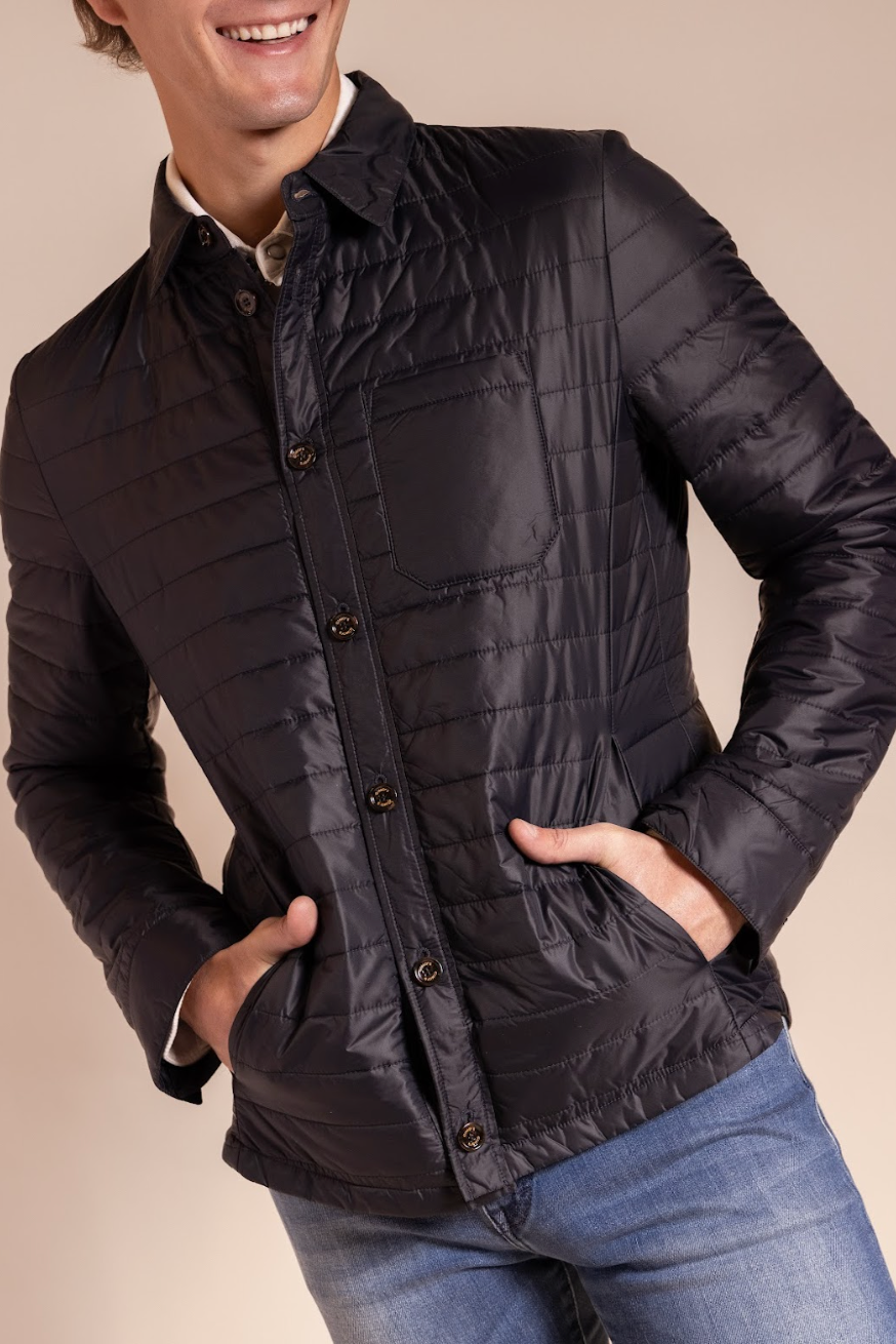 Man wearing a black quilted jacket with a beige background