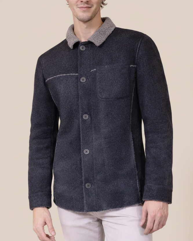 Man wearing a dark blue jacket with a gray collar against a beige background