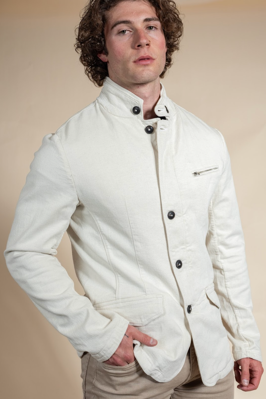 Man wearing a white jacket with black buttons against a beige background