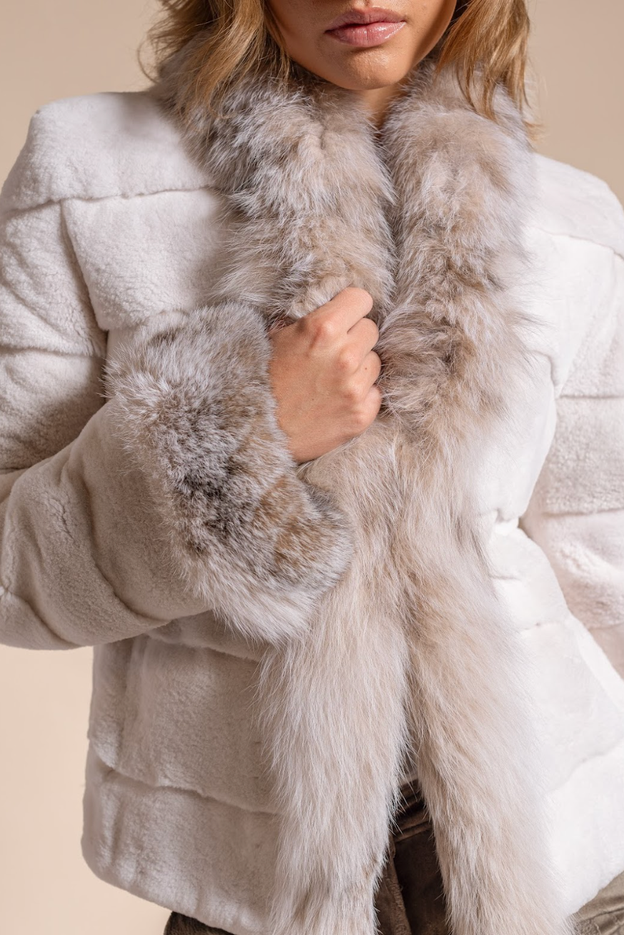 Close-up of a person wearing a white coat with fur trim on a beige background