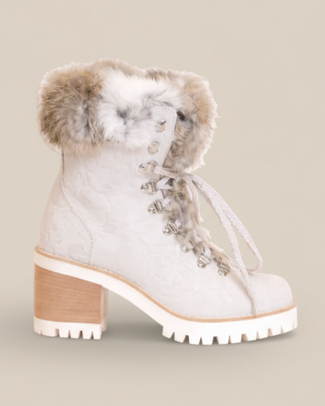 White winter boot with fur trim and decorative elements on a white background