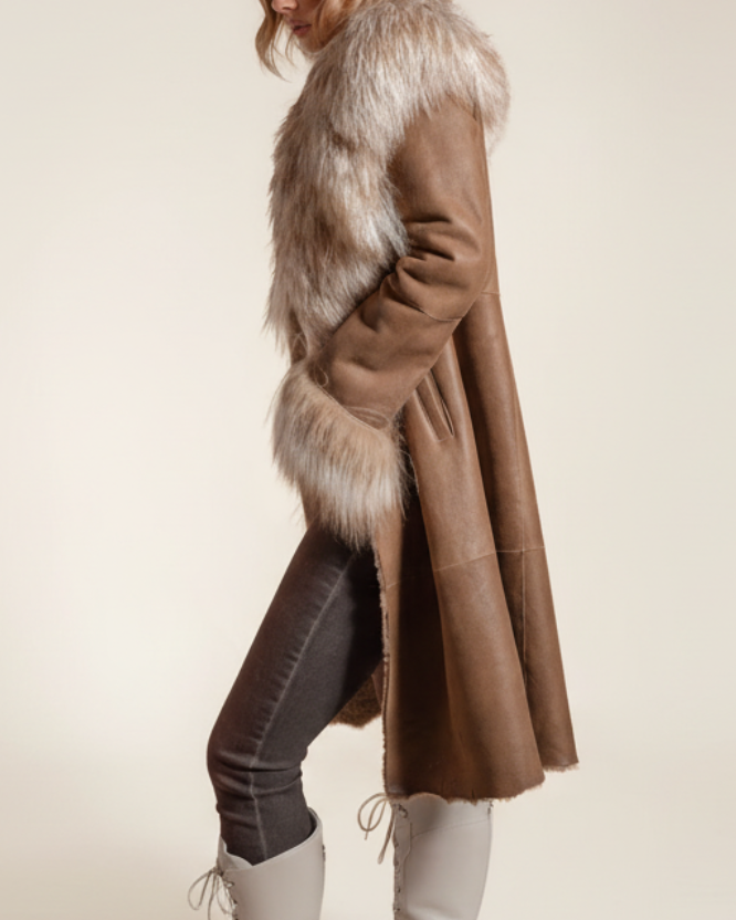 Woman wearing a long brown coat with fur trim on a beige background
