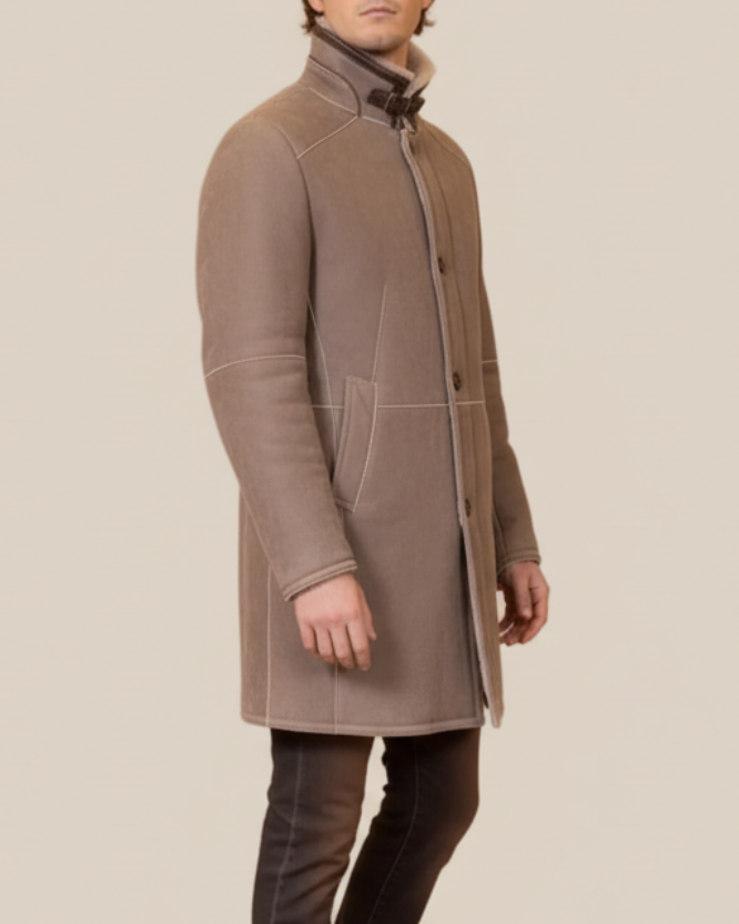 Man wearing a brown coat standing against a beige background