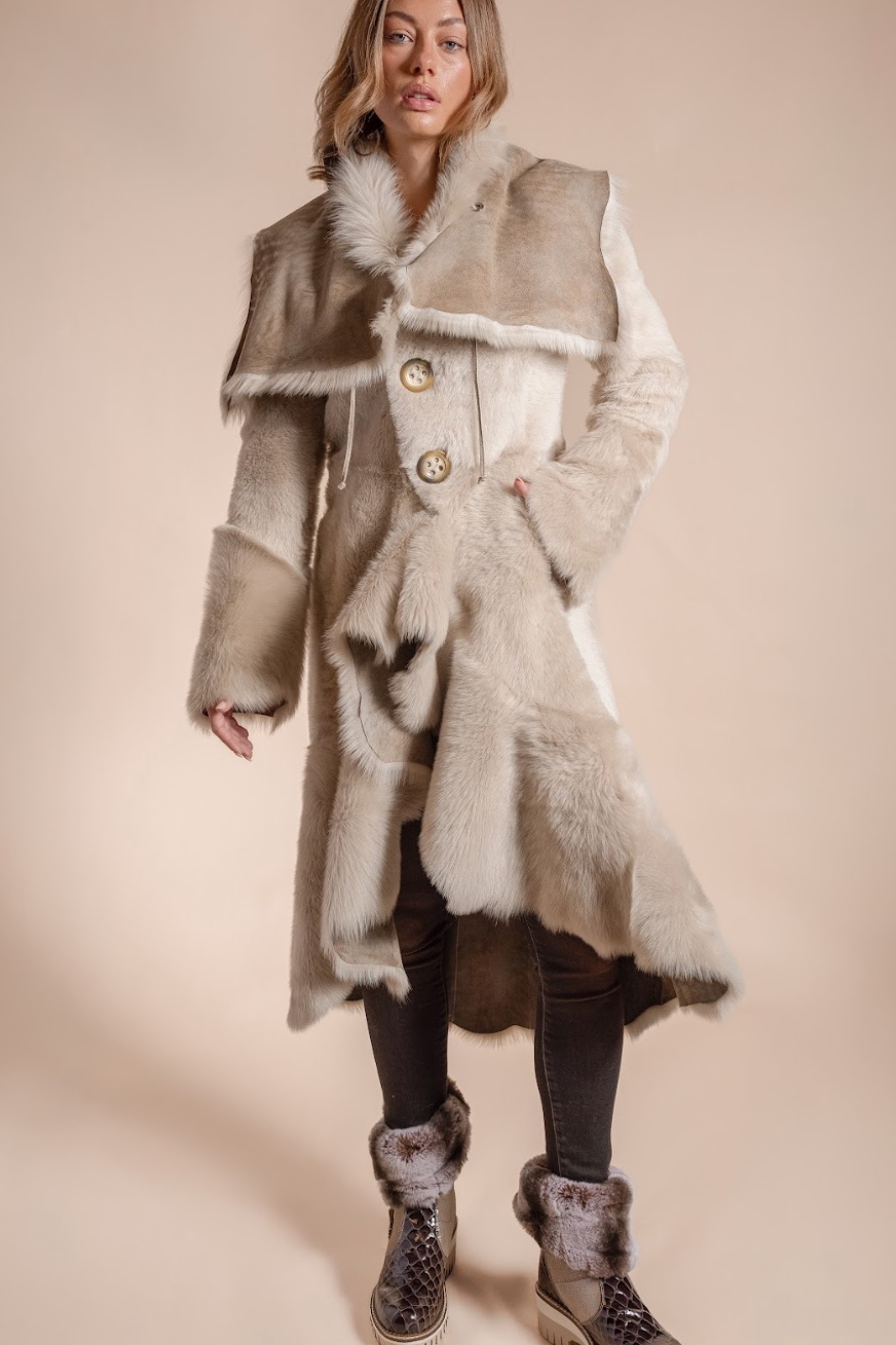 Woman wearing a long fur coat with a neutral background