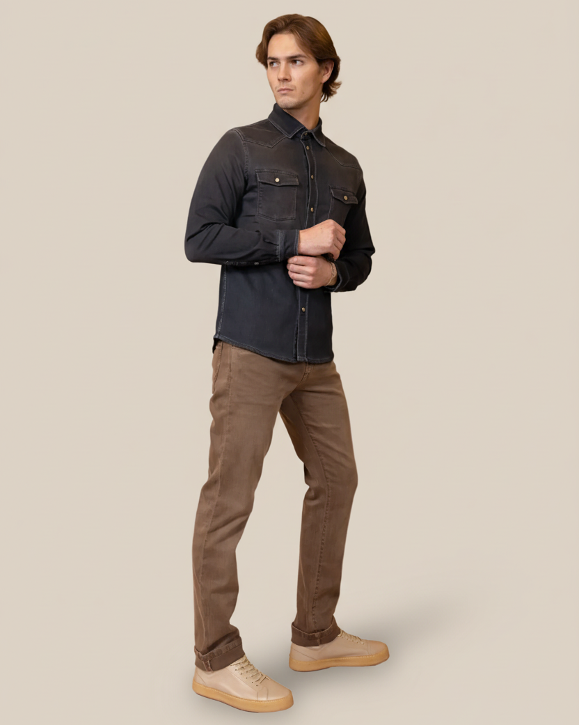Man wearing a dark denim shirt and brown pants on a beige background
