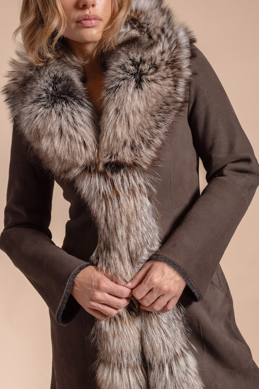 Brown coat with a fur scarf against a beige background