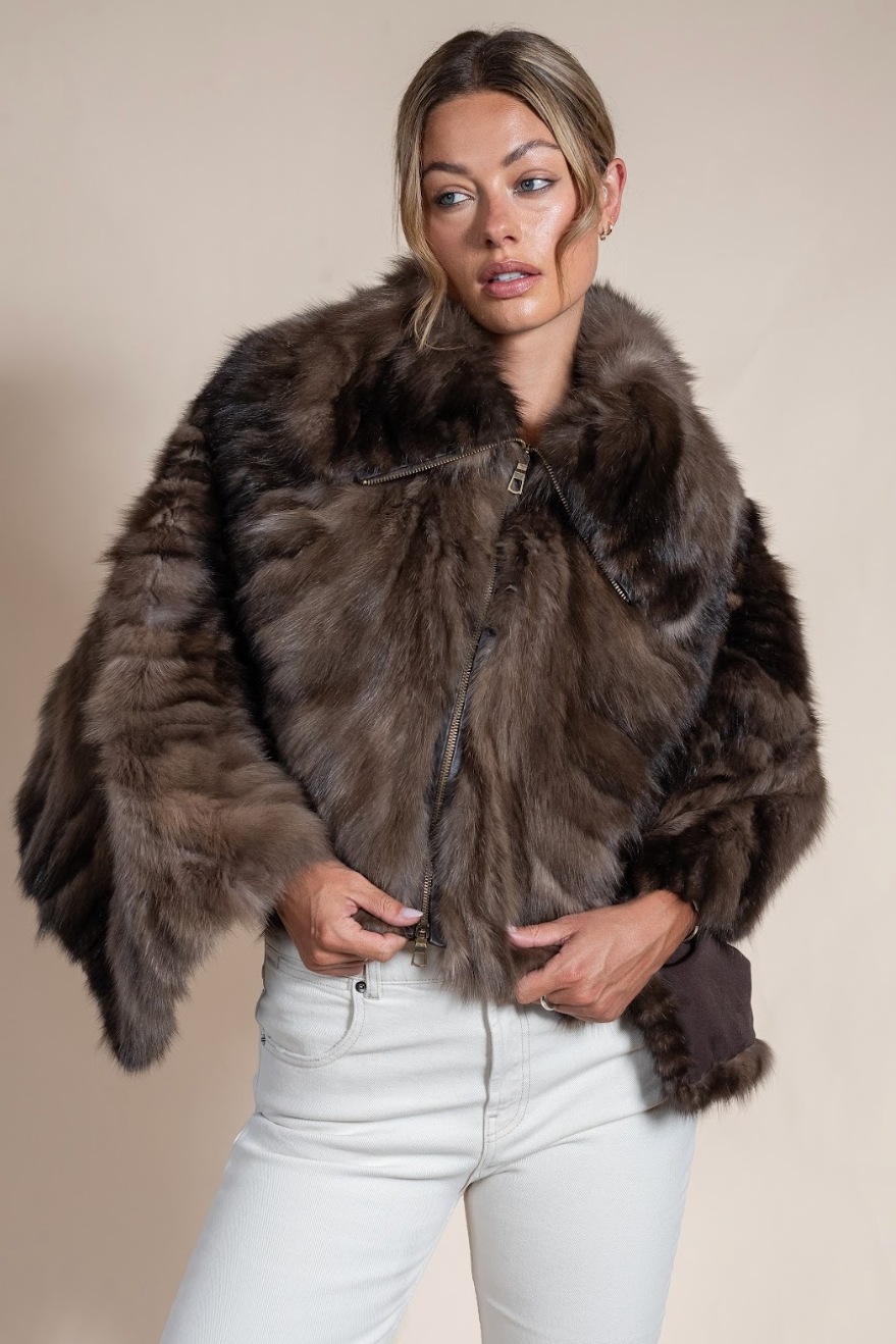 Woman wearing a brown fur jacket against a beige background