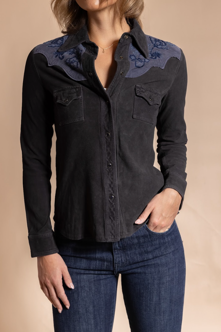Black button-up shirt with floral embroidery on a beige background