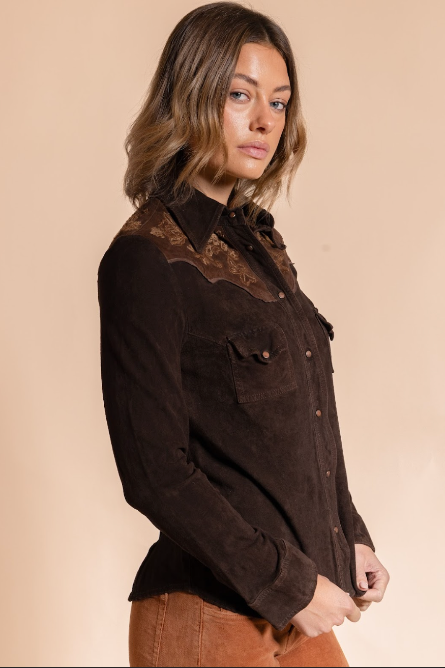 Woman wearing a brown jacket with intricate detailing on a beige background