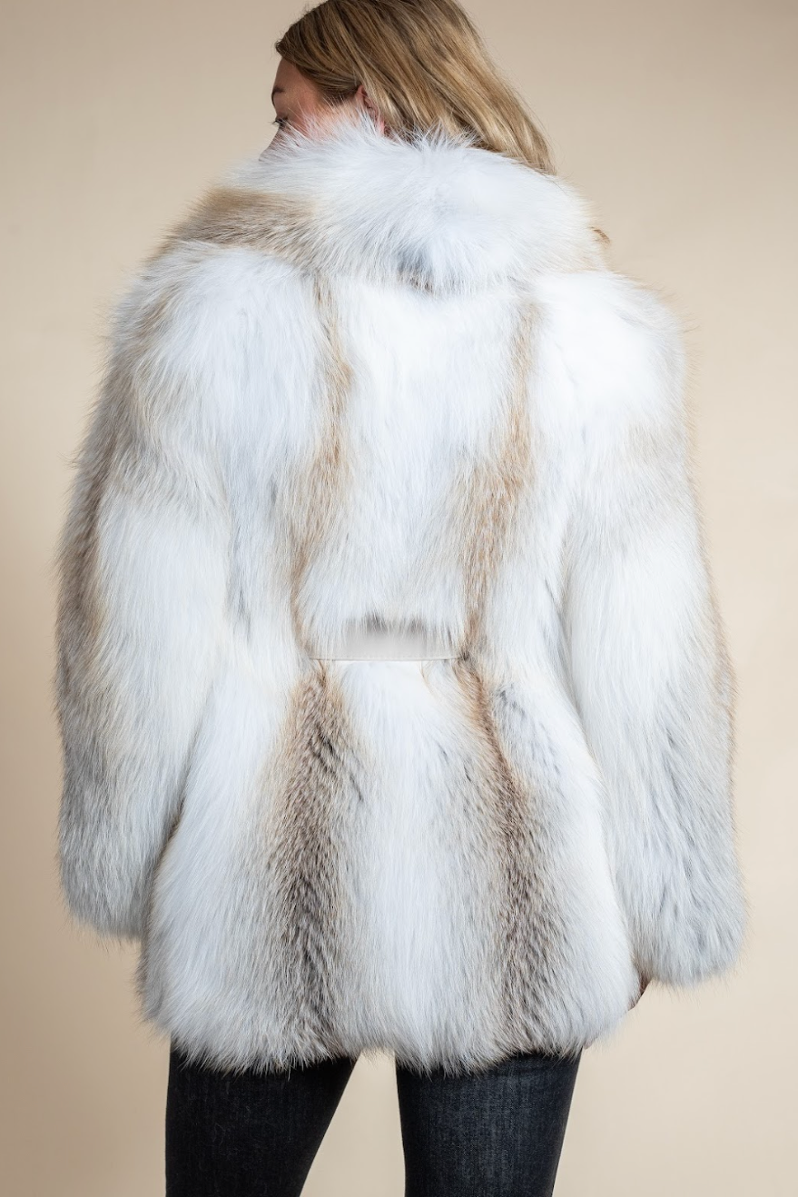 White fur coat with brown accents worn by a person on a beige background