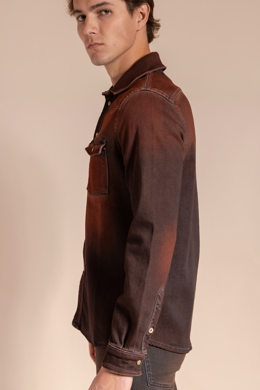 Man wearing a brown denim shirt with rolled-up sleeves on a beige background