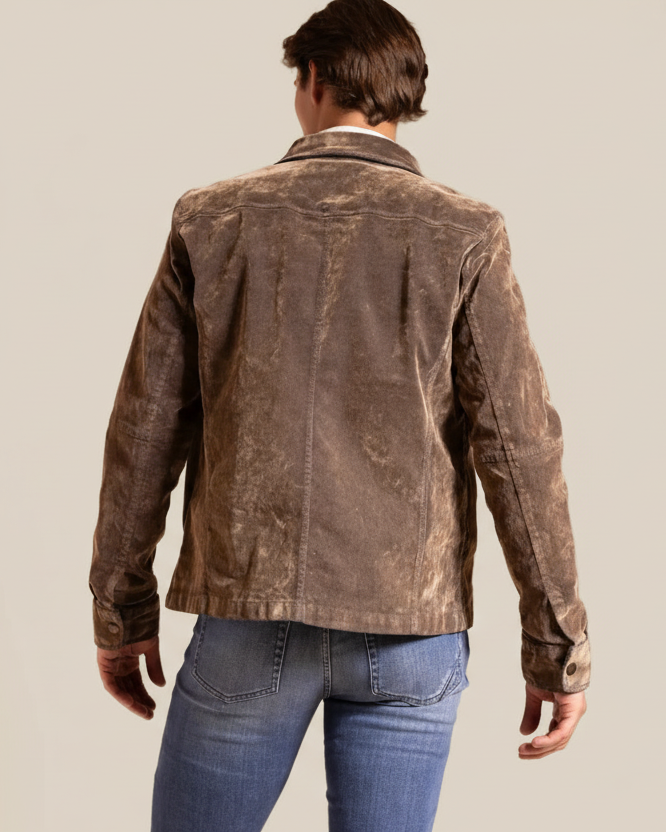 Person wearing a brown jacket and blue jeans on a beige background