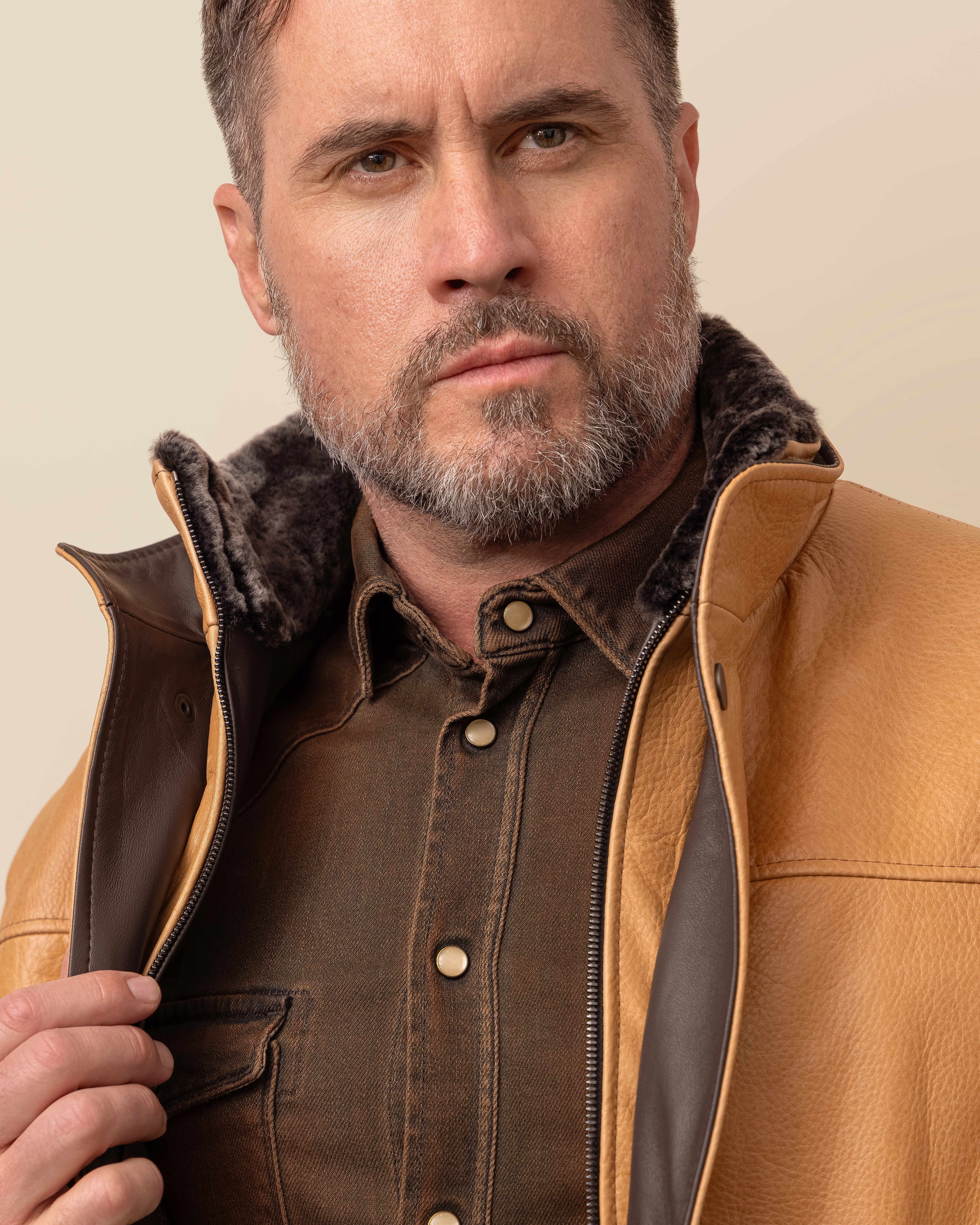 Man wearing HYDE Canyon waxy camel cowhide jacket — tailored fit, grey shearling collar, wool-cashmere lining, sizes 36–52