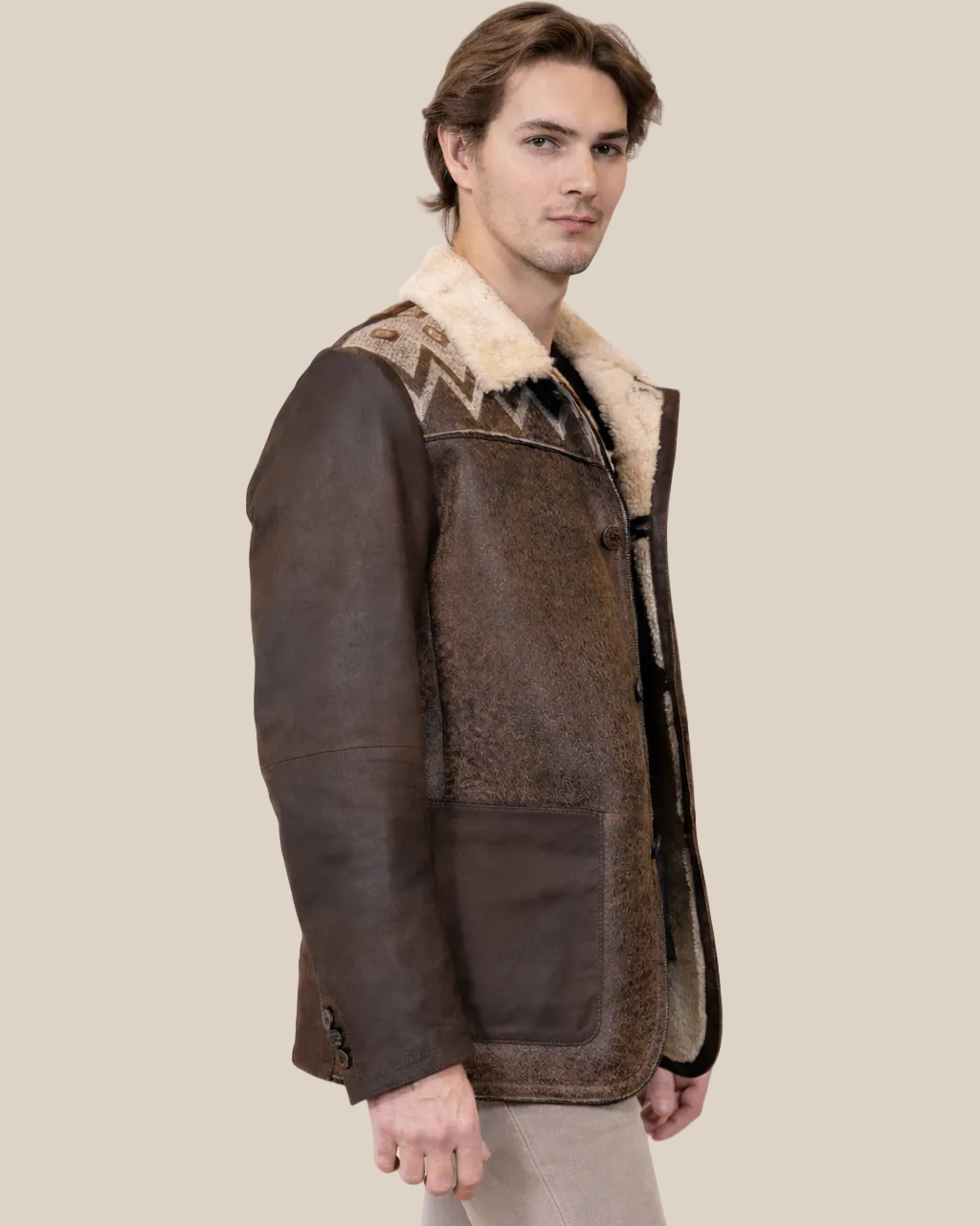 Man wearing a brown leather jacket with fur lining on a beige background