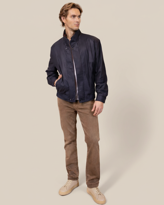 Man wearing a navy jacket and brown pants on a beige background