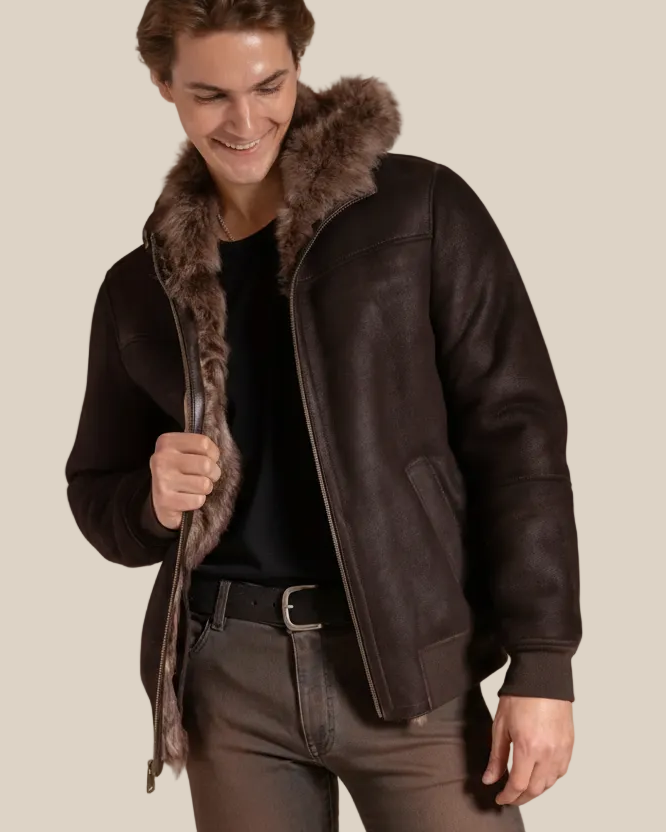 Man wearing a dark brown leather shearling jacket on a beige background