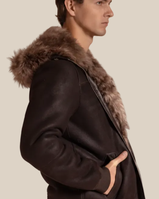 Man wearing a dark brown leather shearling jacket on a beige background