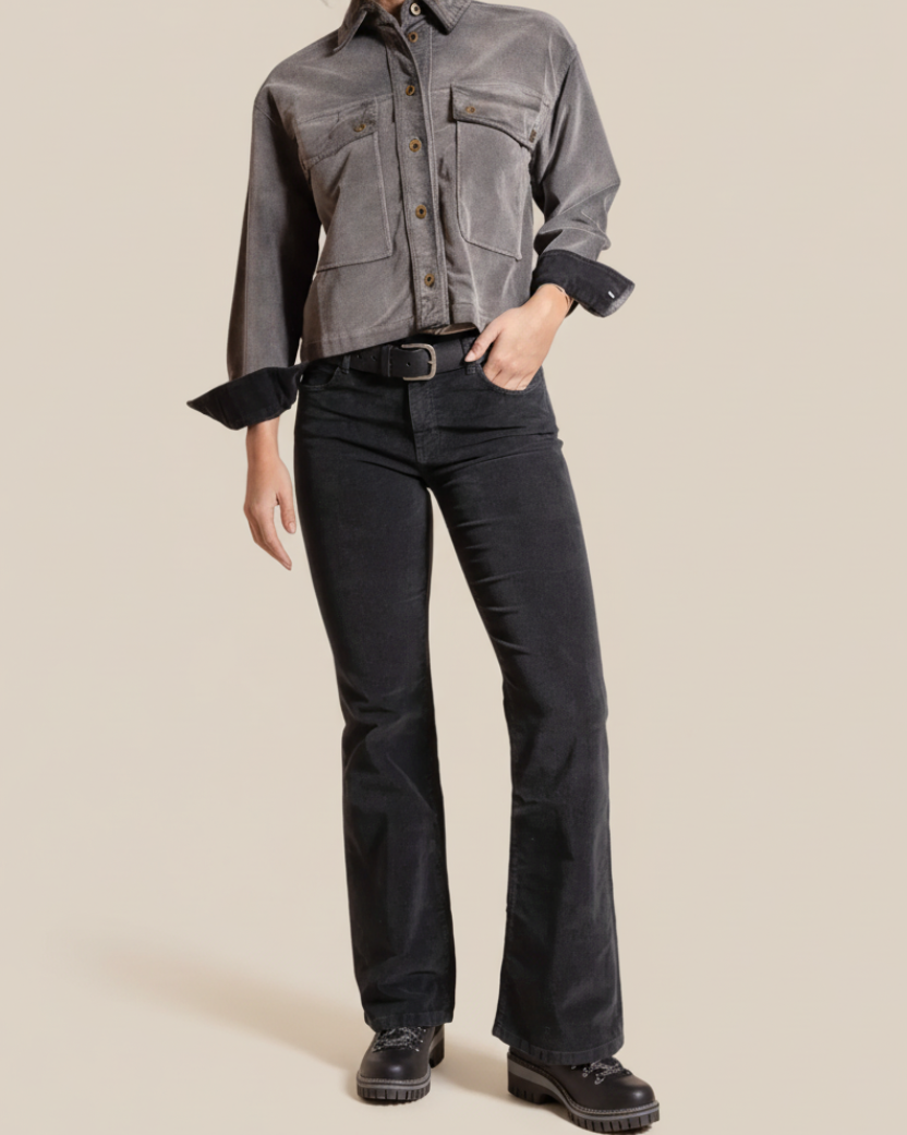 Person wearing a gray jacket and black pants on a beige background