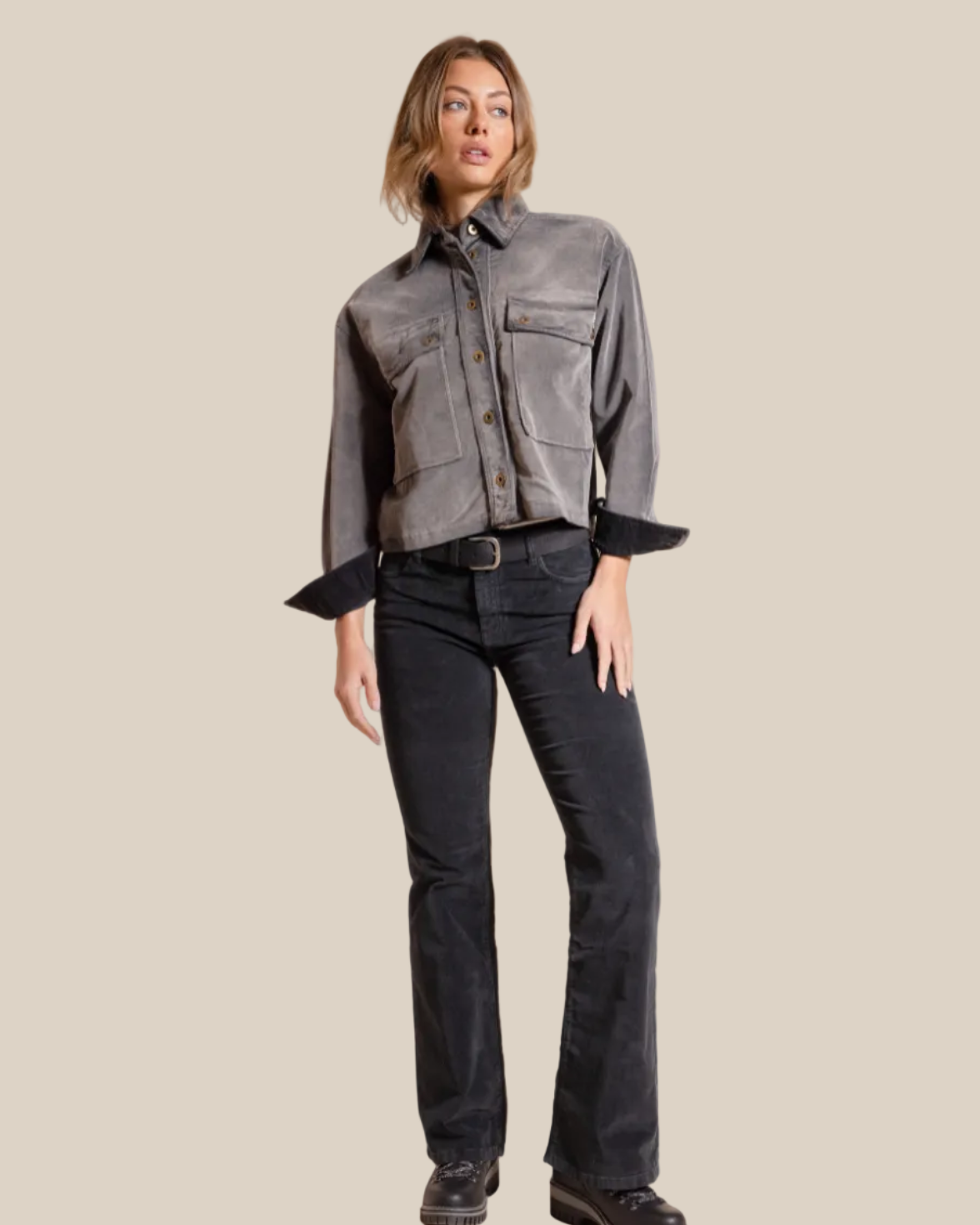 Woman wearing a gray shirt and black pants against a beige background