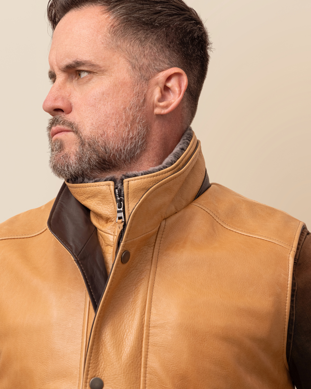 HYDE Range Vest — three-quarter view showing fold-over snap button panel and zip closure, waxy camel cowhide, wool-cashmere lined